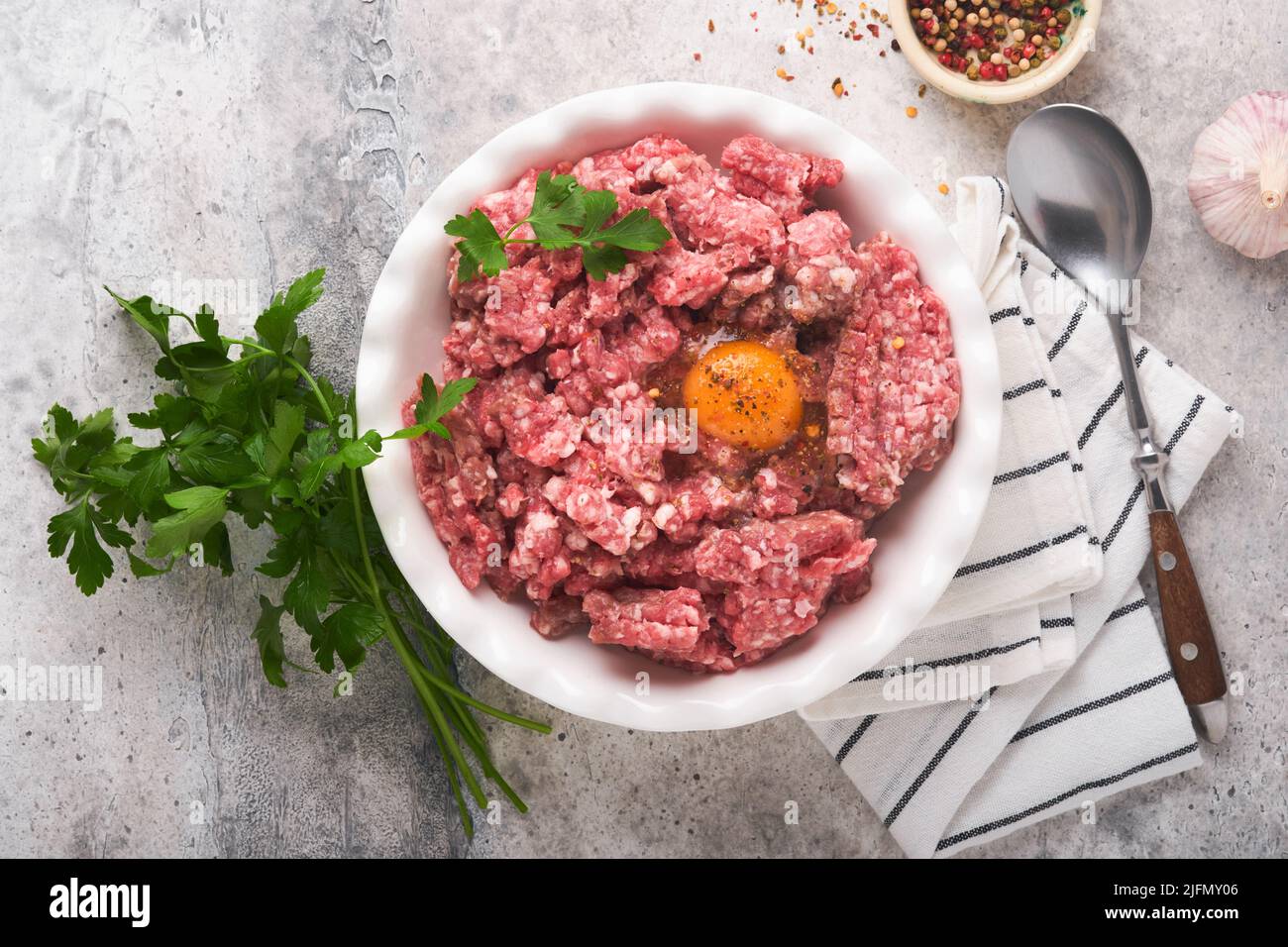 Viande hachée crue. Viande hachée de bœuf, porc ou épices d'agneau, herbes et œufs sur plaque blanche sur fond de béton gris clair. Viande fraîche hachée prête pour c Banque D'Images Viande hachée crue. Viande hachée de bœuf, porc ou épices d'agneau, herbes et œufs sur plaque blanche sur fond de béton gris clair. Viande fraîche hachée prête pour c Banque D'Images