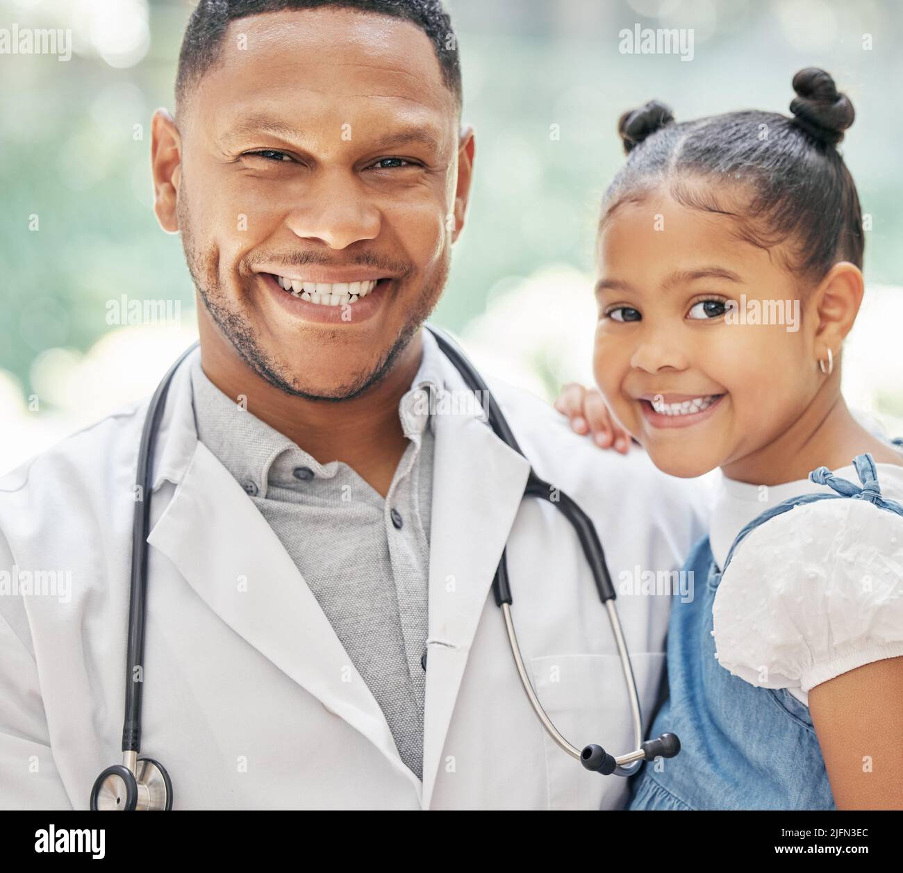 Portrait d'un jeune pédiatre noir élégant tenant une adorable petite fille dans les mains, un enfant mignon et un médecin souriant pendant le contrôle médical à la clinique Banque D'Images