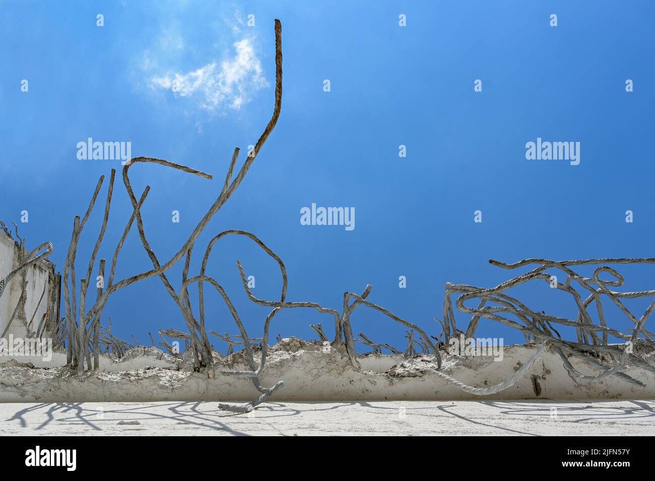 Barres d'armature en fer rouillé sortant d'un mur de béton cassé contre un ciel bleu, concept abstrait de grunge pour la décomposition, bâtiments infinis ou architecte Banque D'Images