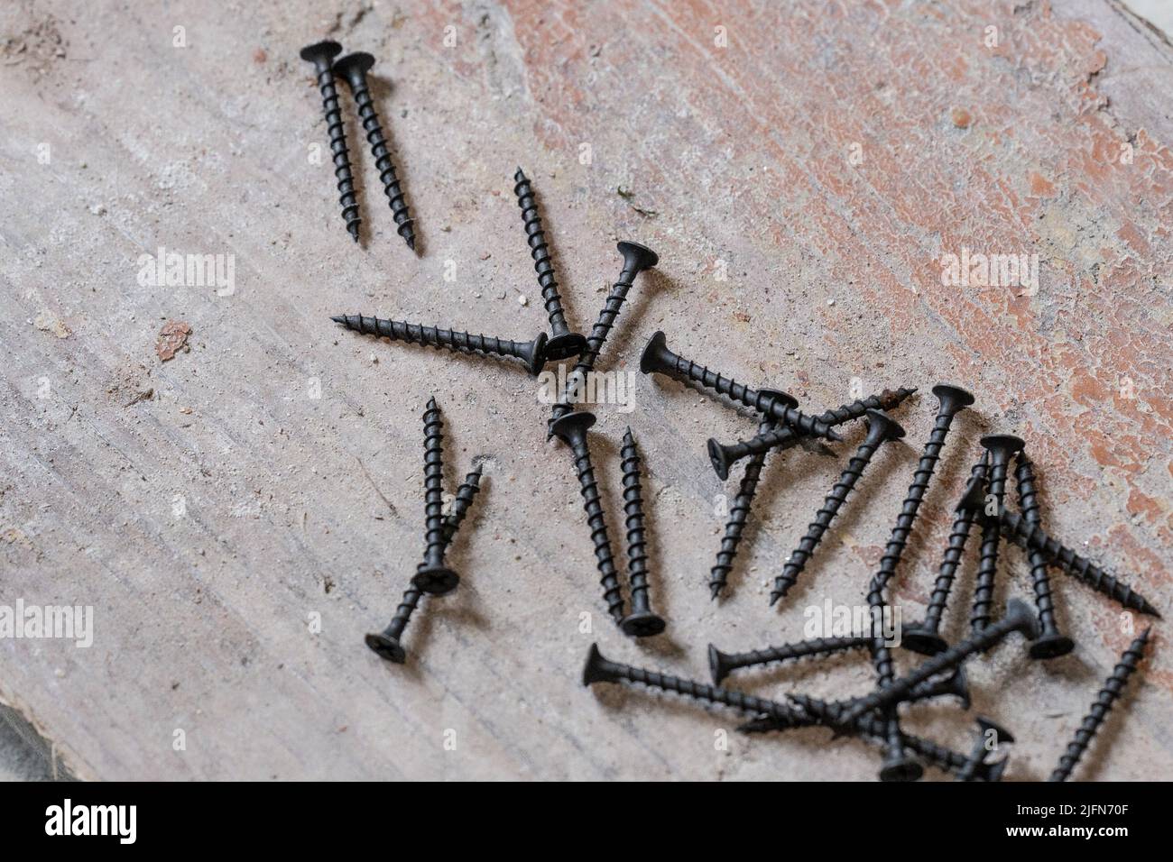 Les vis en métal noir se trouvent sur le sol en béton, les vis sur le bois  Photo Stock - Alamy