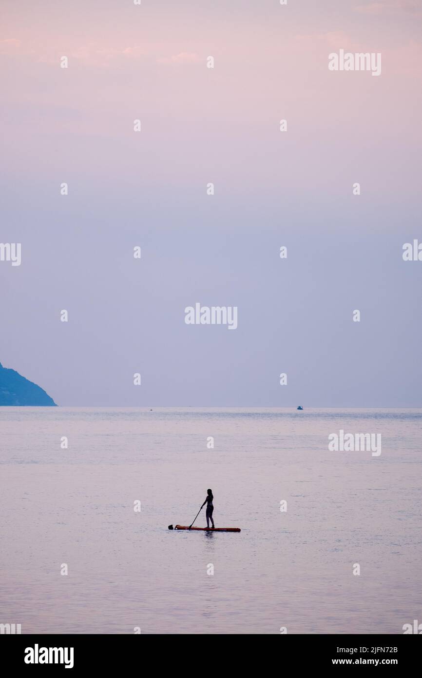Scène de coucher de soleil avec une femme sur son stand en paddleboard Banque D'Images