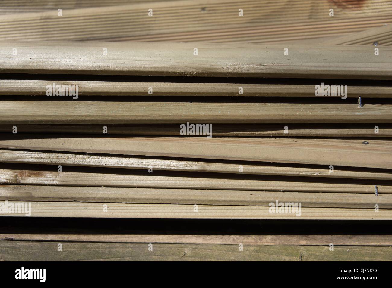 Gros plan de bois empilé. Le bois utilisé d'une ancienne clôture de jardin a encore quelques vis dans elle. Les lattes forment un motif géométrique intéressant. Banque D'Images