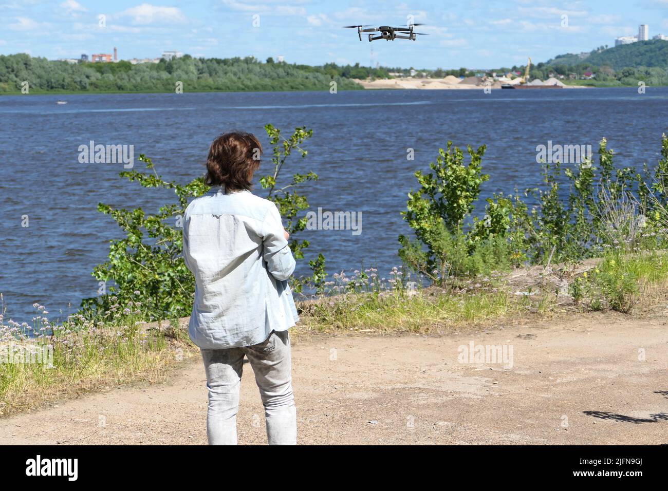 Une fille, pilote de drone, contrôle un quadricoptère dans la rue en été par temps ensoleillé. Banque D'Images