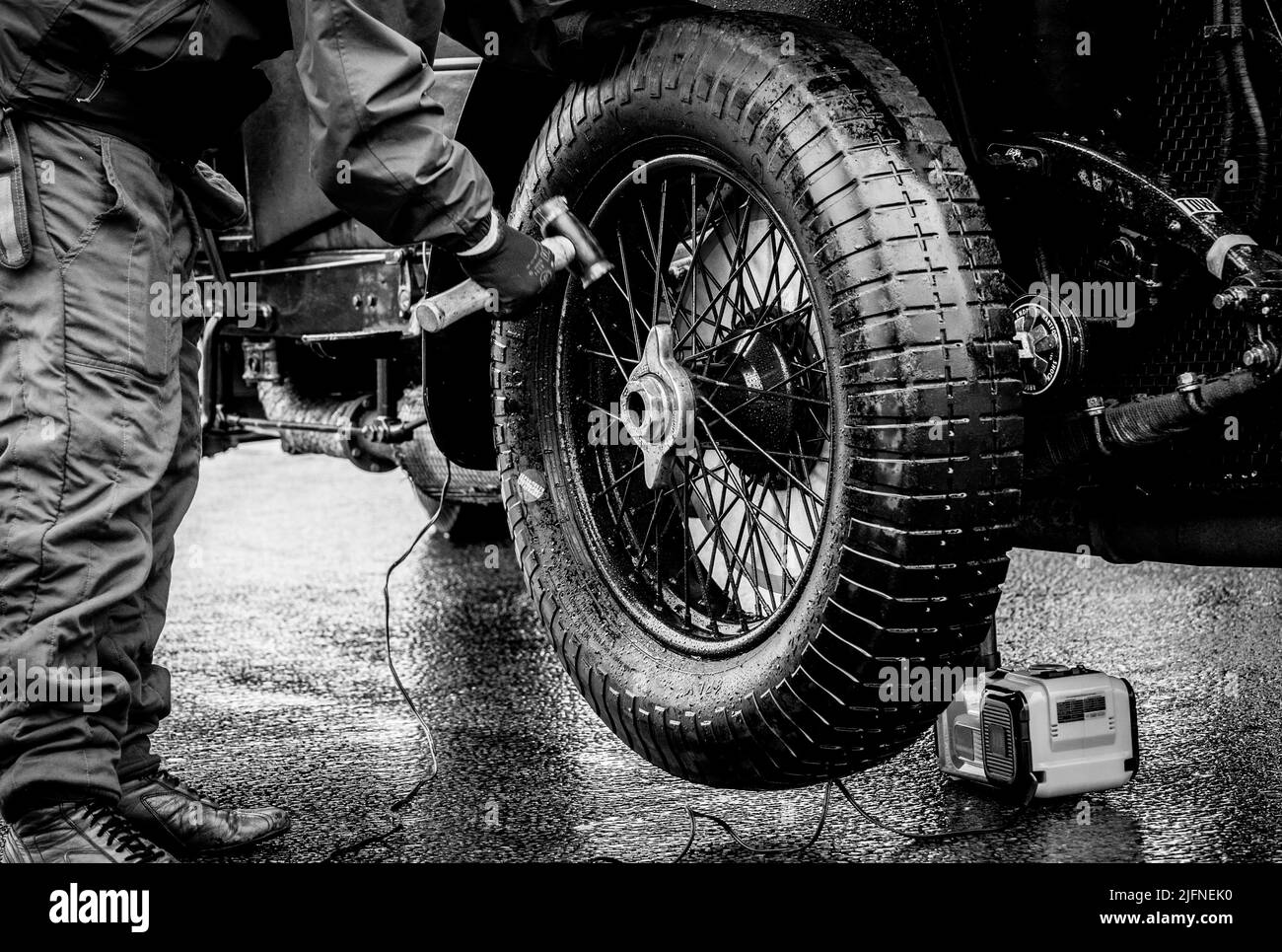 Mechcanic à l'aide d'un marteau en cuivre pour fixer l'écrou de roue à une voiture Bentley d'époque de 4,5 litres sous la pluie. Banque D'Images