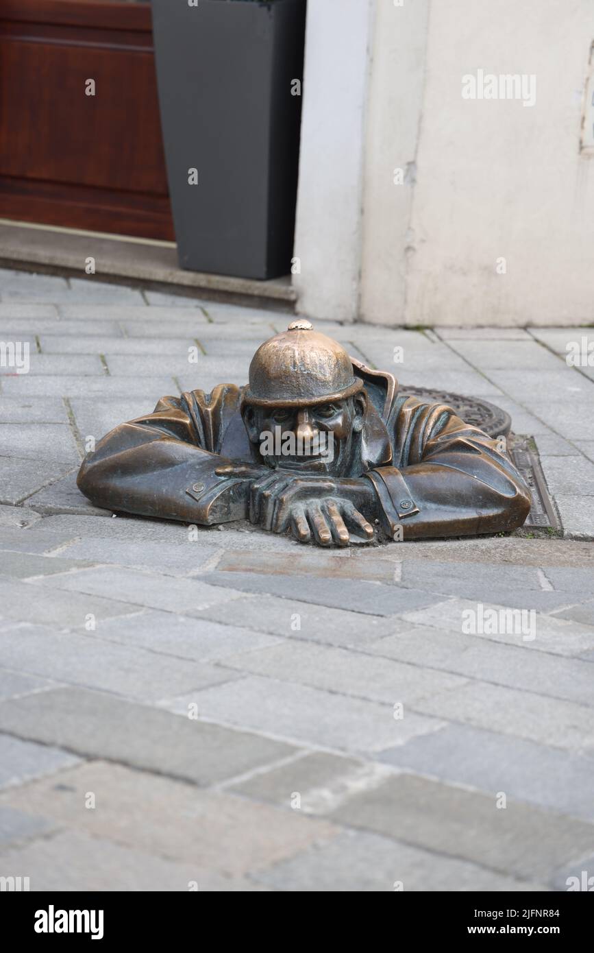 Statue en bronze excentrique (1997) d'un ouvrier d'égout (Čumil, l'observateur) émergeant d'un trou d'homme dans le centre de Bratislava, Slovaquie. Est-ce un tom pépirant ? Banque D'Images