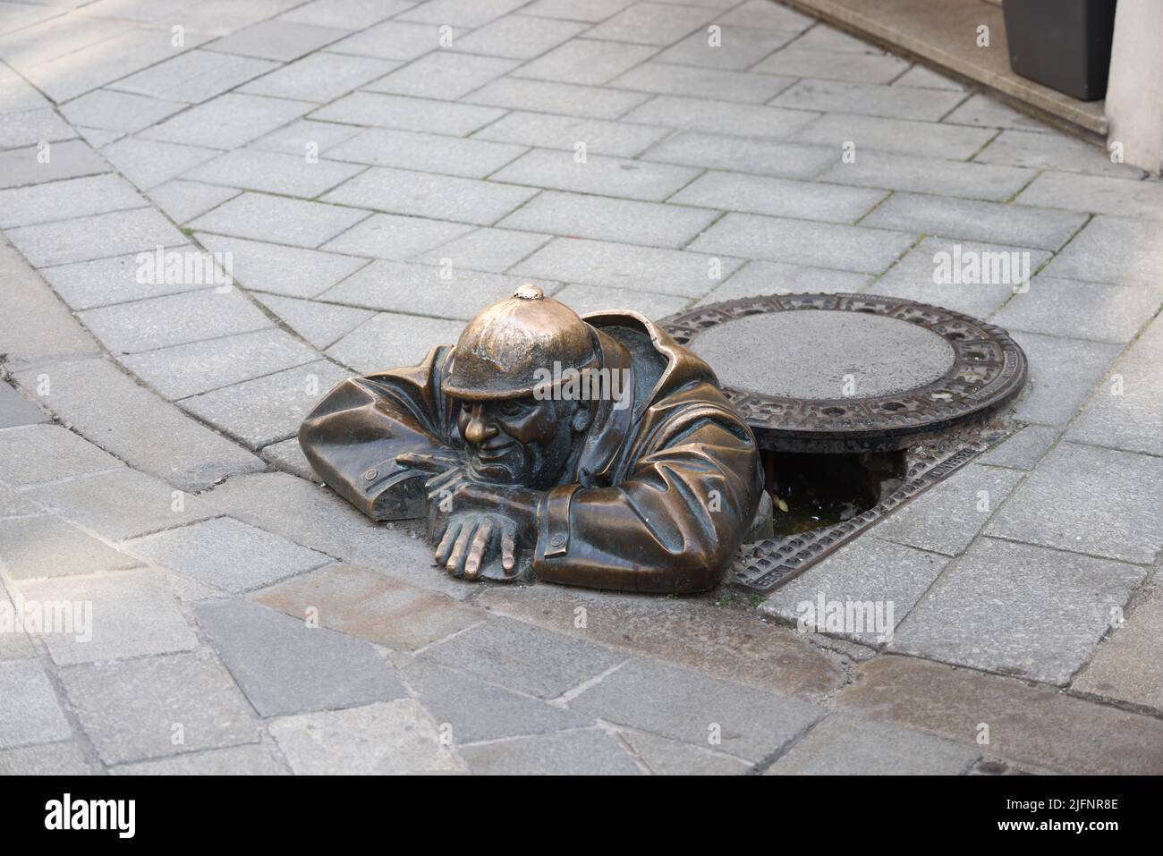 Statue en bronze excentrique (1997) d'un ouvrier d'égout (Čumil, l'observateur) émergeant d'un trou d'homme dans le centre de Bratislava, Slovaquie. Est-ce un tom pépirant ? Banque D'Images