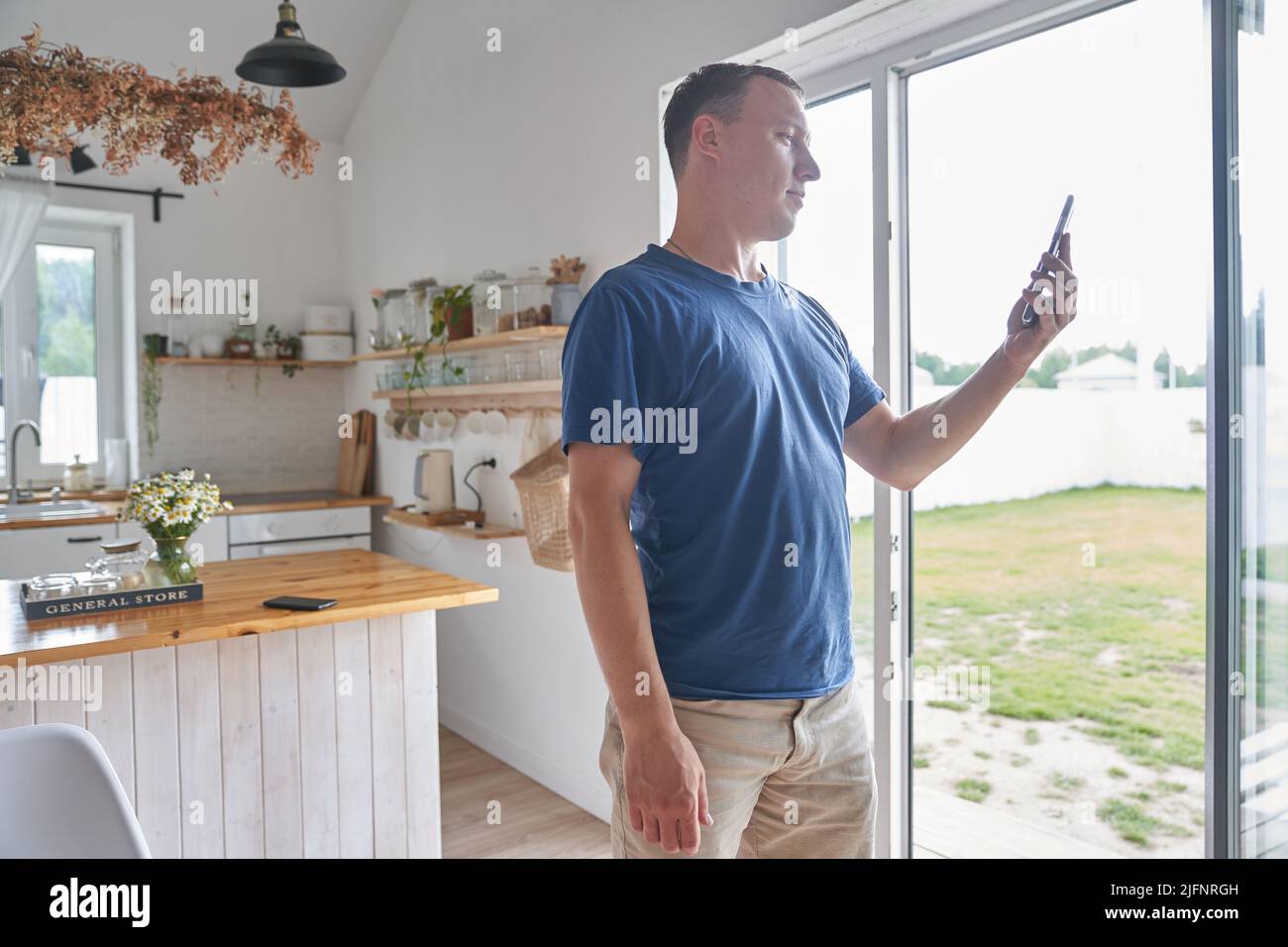 Un jeune homme travaillant à distance depuis son bureau à domicile regarde des informations sur son téléphone. Un homme tient un smartphone entre ses mains et le regarde. Photo de haute qualité Banque D'Images