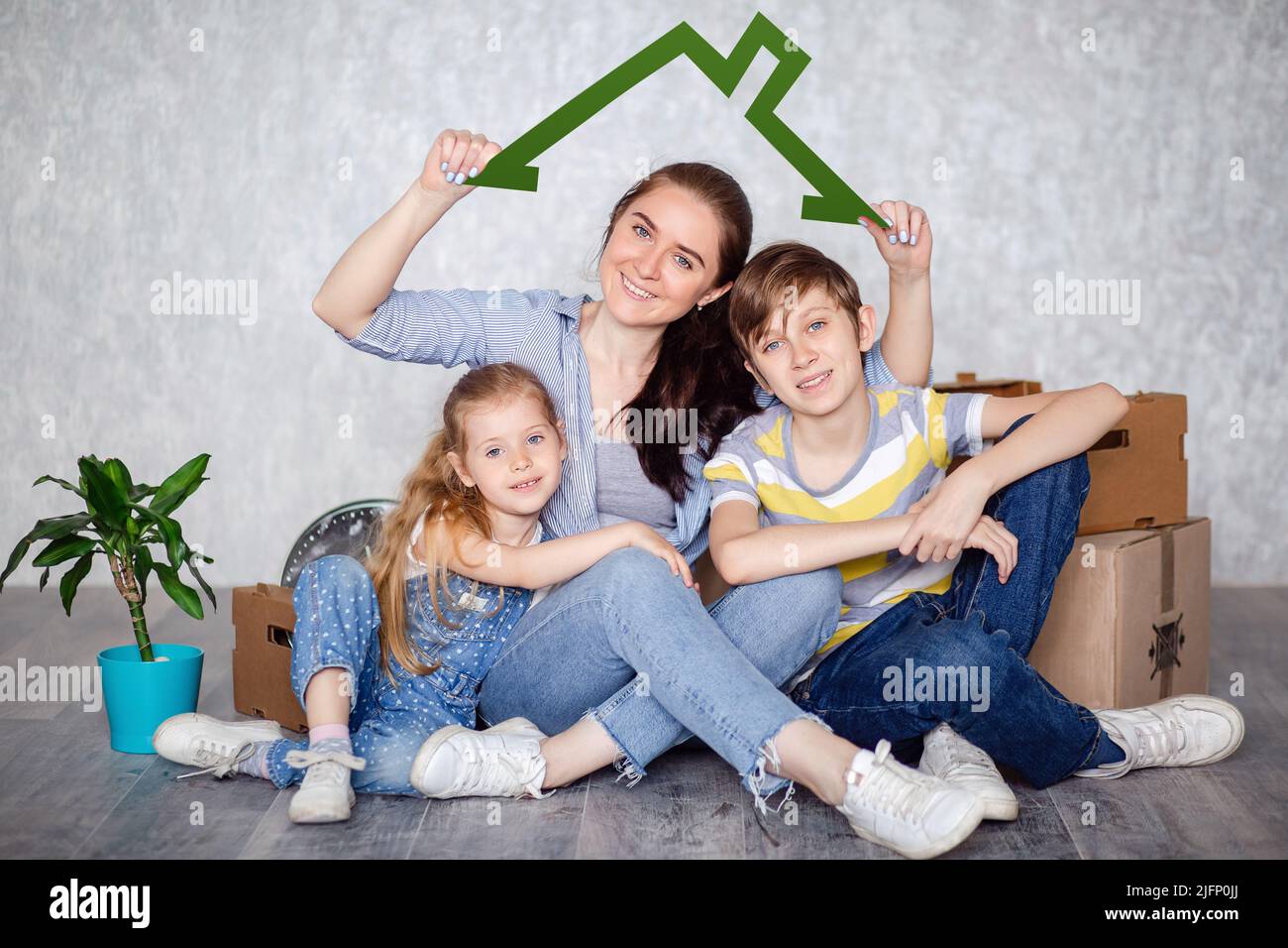 Une mère avec son fils et sa fille se déplace dans un nouvel appartement avec des choses dans des boîtes en carton. La famille crée un toit qui promet excellent Banque D'Images