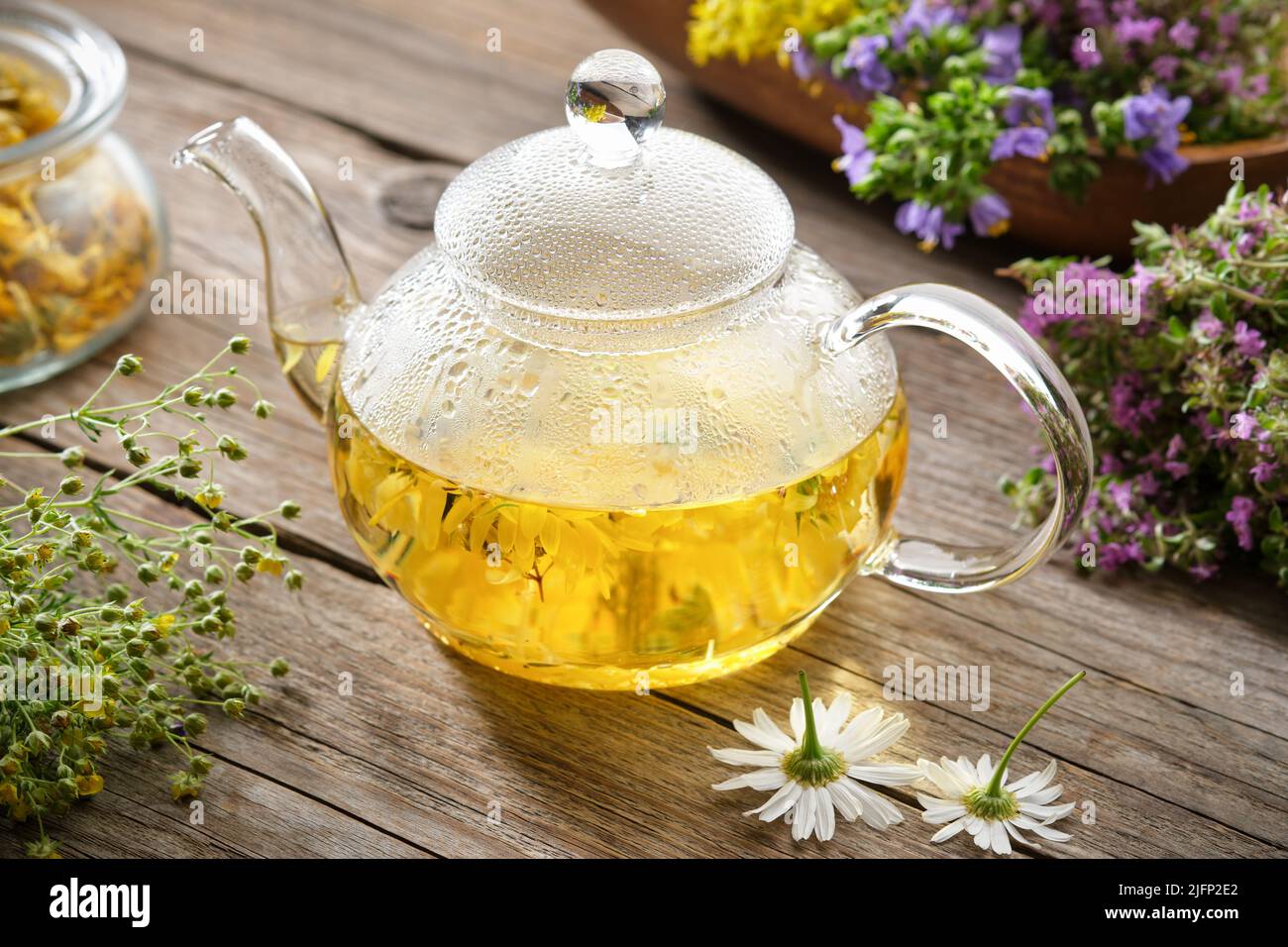 Thé en verre bouilloire de thé à base de plantes saines, camomille, calendula, fleurs de thym sur table en bois. Médecine alternative à base de plantes. Banque D'Images