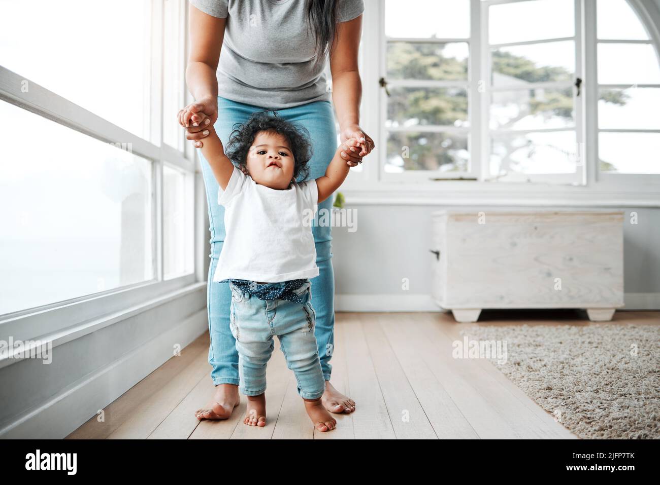 En la regardant, elle fait ses premiers pas. Photo d'une petite fille apprenant à marcher avec l'aide de sa mère. Banque D'Images