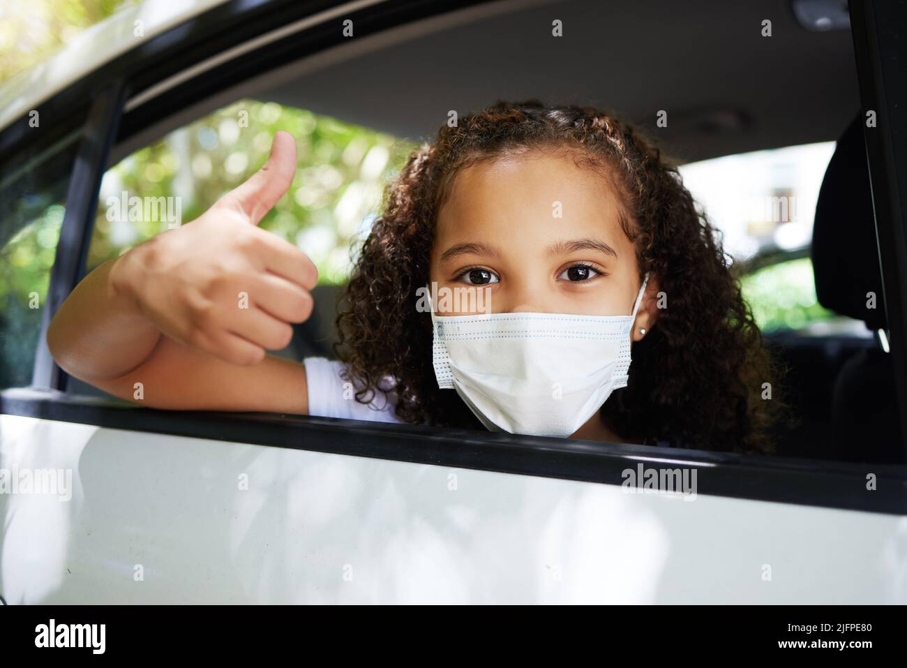 La sécurité avant tout. Portrait court d'une adorable petite fille donnant des pouces par la fenêtre arrière d'une voiture. Banque D'Images