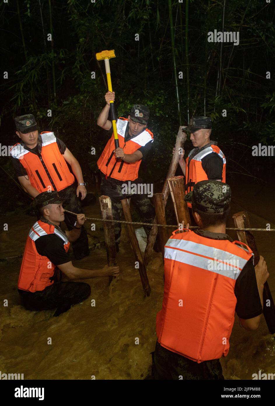 BEIHAI, CHINE - le 4 JUILLET 2022 - des policiers et des soldats armés utilisent des sacs de sable, des piquets et des planches de bois pour construire un barrage pour bloquer la brèche à Beihai Banque D'Images