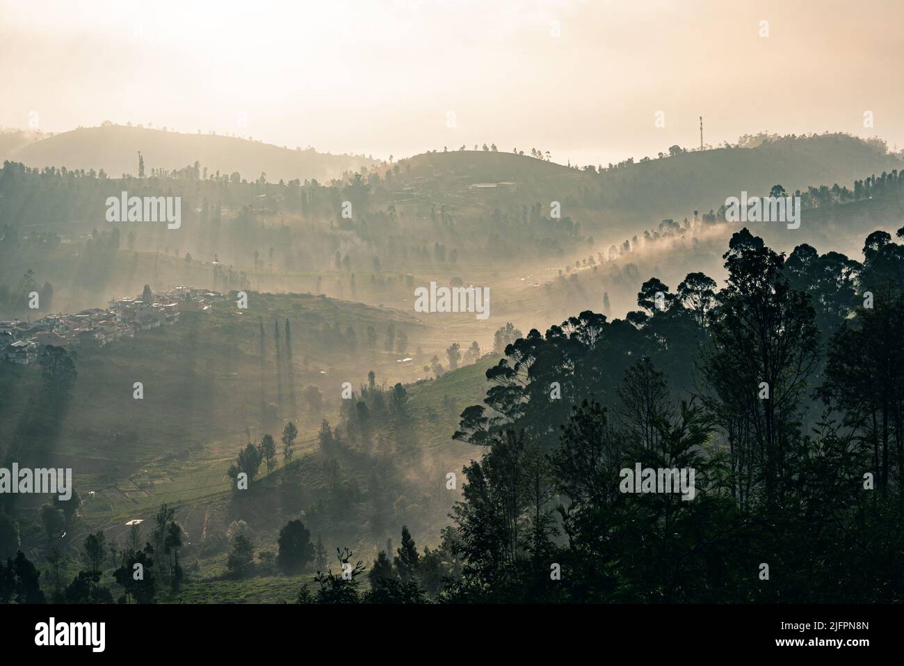 Une vue au lever du soleil depuis les collines Ooty avec un ciel spectaculaire et la lumière du soleil chaude passant par la brume dans le paysage Banque D'Images