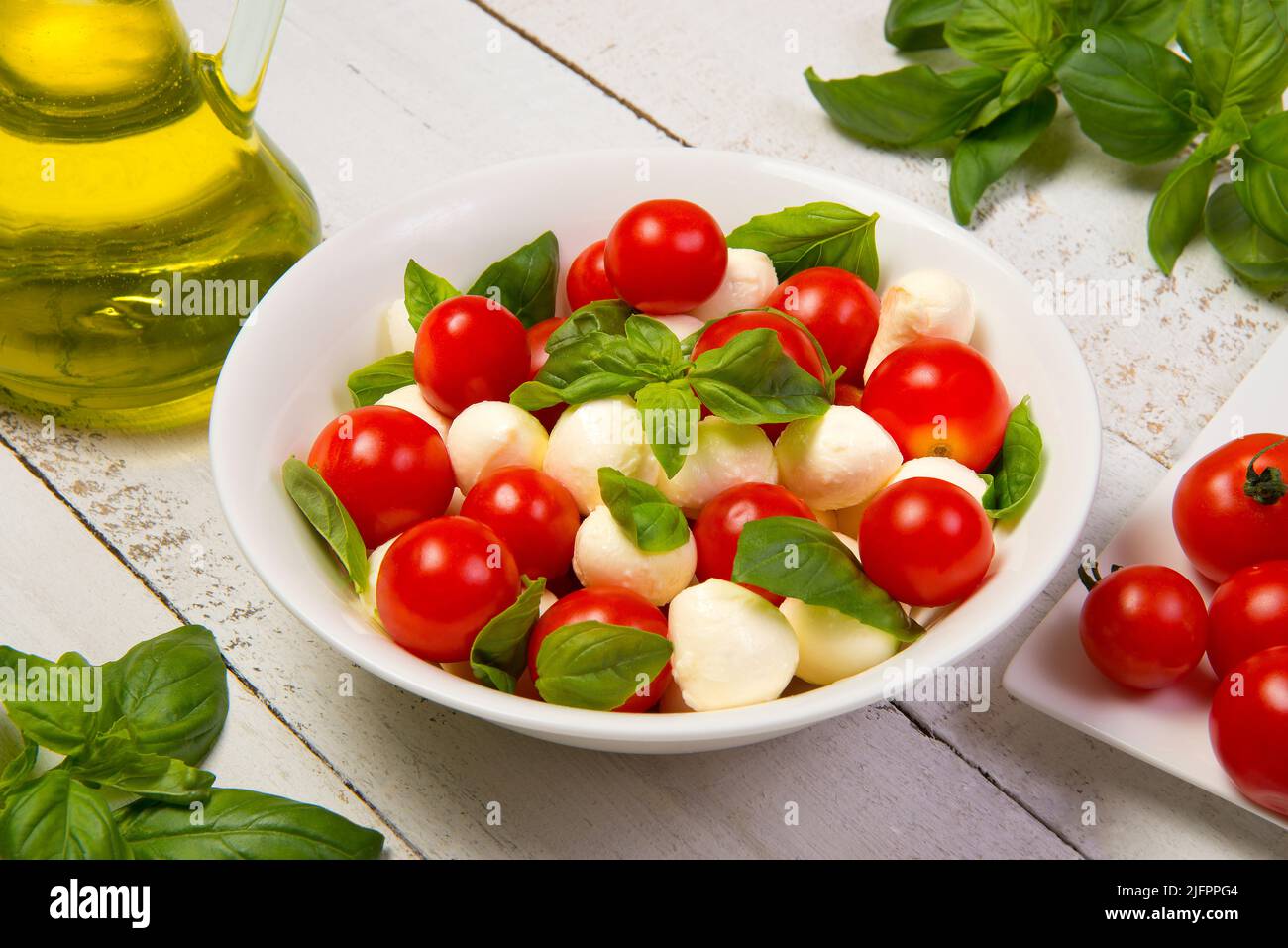 Salade Caprese dans un saladier blanc rond sur une table en bois blanc. Mise au point sélectionnée. Banque D'Images