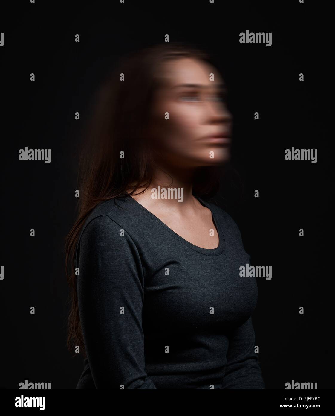 Qui suis I. Studio photo d'une femme debout sur un fond noir avec un visage flou. Banque D'Images