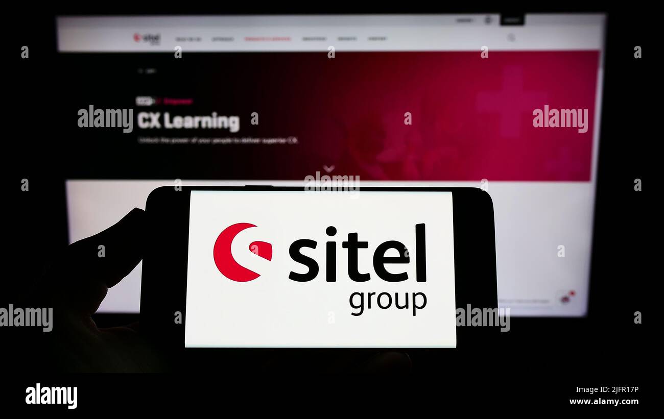 Personne tenant un smartphone avec le logo de la société américaine de centre d'appels Sitel Group sur l'écran devant le site Web. Mise au point sur l'affichage du téléphone. Banque D'Images