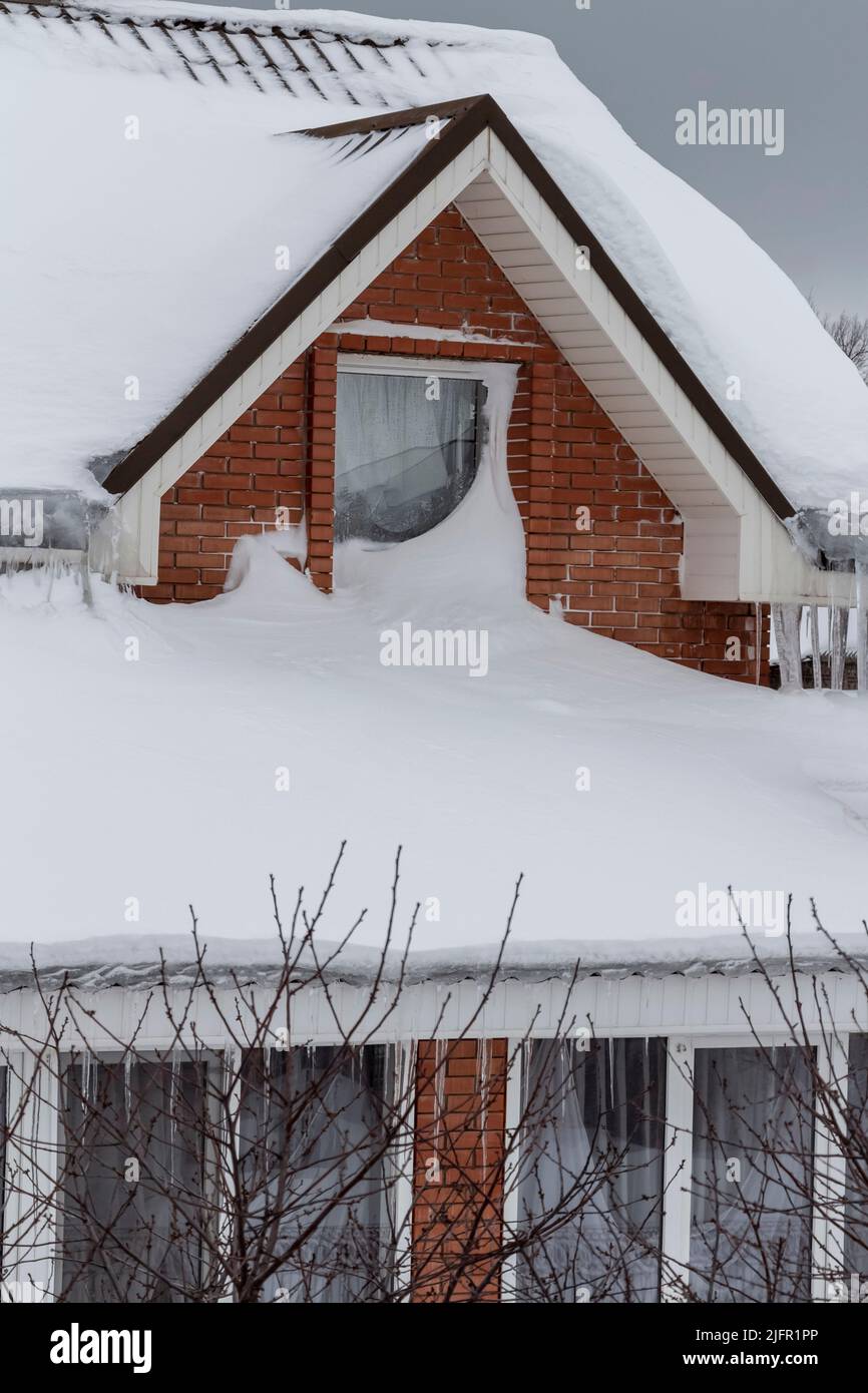 Le toit d'une maison privée sous une épaisse couche de neige. Banque D'Images