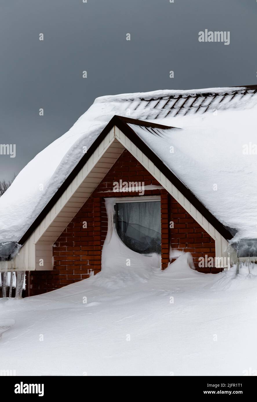Le toit d'une maison privée sous une épaisse couche de neige. Banque D'Images