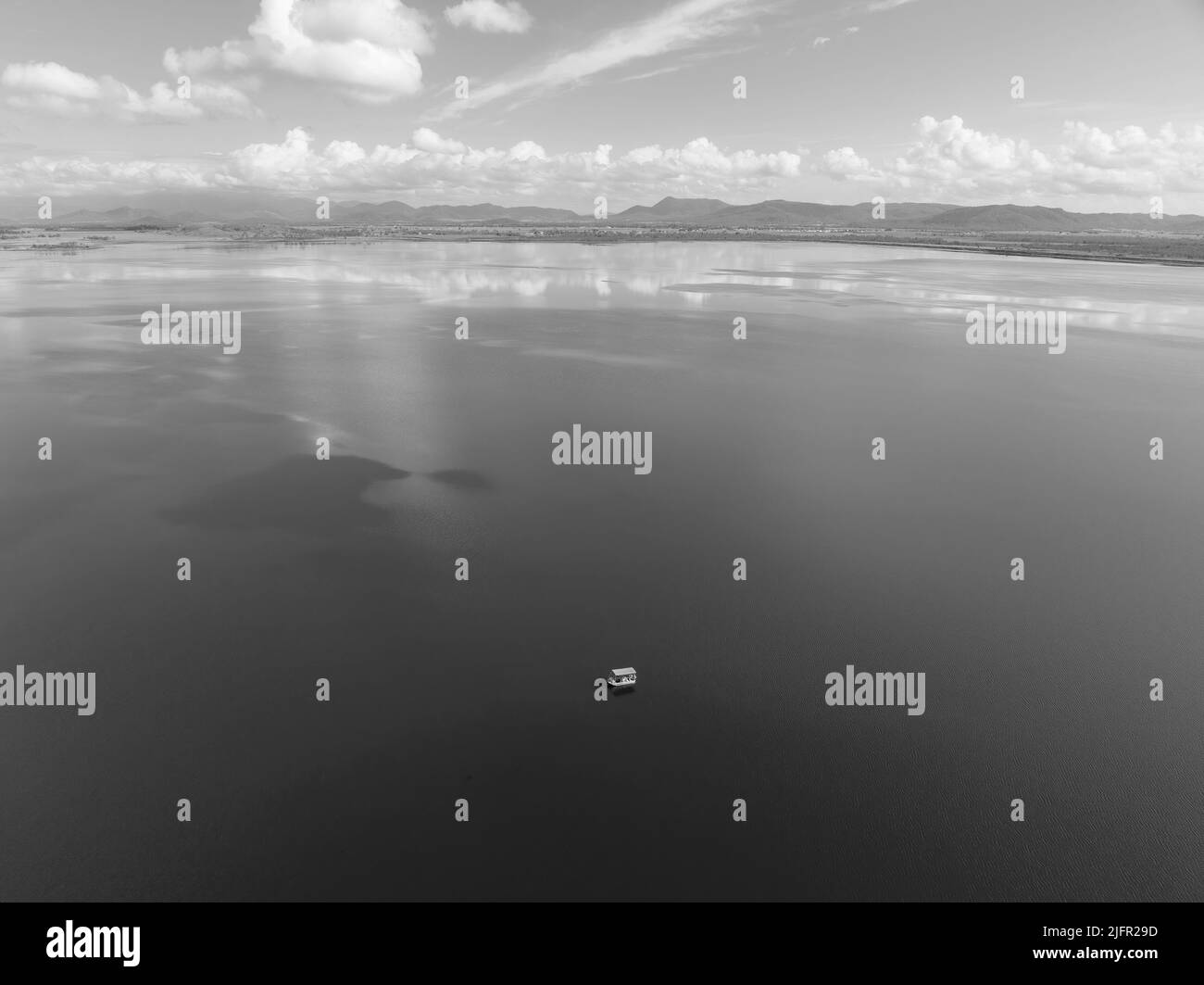 Le drone au-dessus capture les pêcheurs dans un bateau sur un barrage lors d'une journée calme avec des reflets de nuages dans l'eau. Été australien ensoleillé et paisible. Banque D'Images