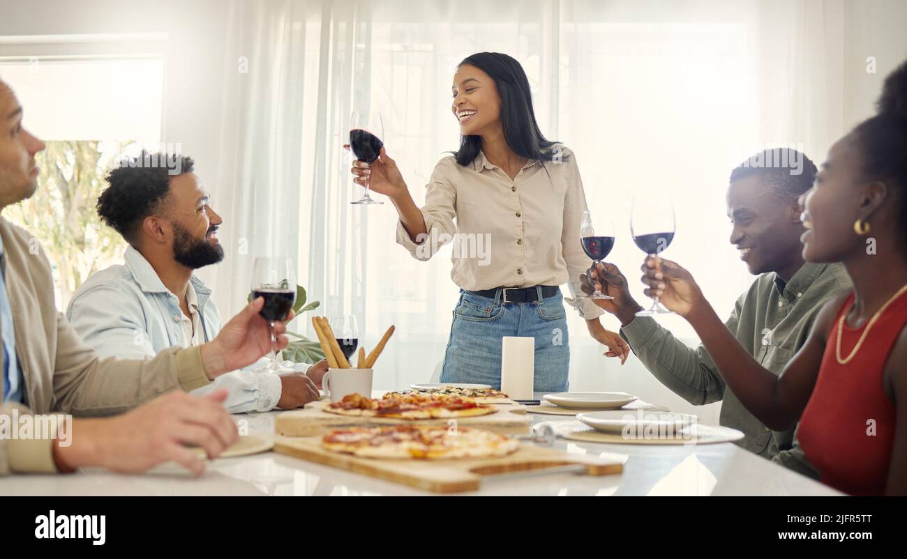 À mes amis qui restent à mes côtés par le bon et le mauvais. Photo d'un groupe de personnes partageant un toast autour de la table à manger dans une maison. Banque D'Images