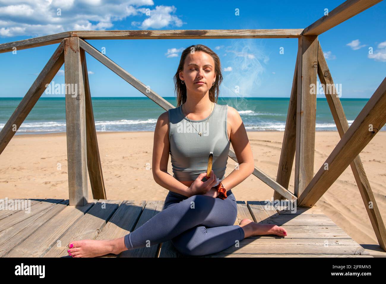 femme méditant par la plage avec un bâton de palo santo Banque D'Images