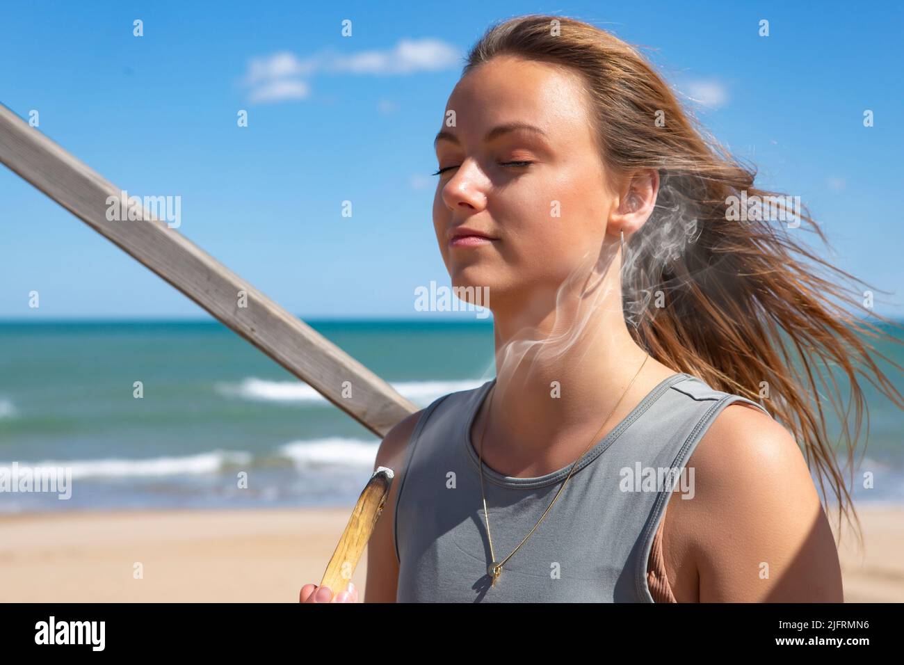belle jeune femme méditant par la plage avec palo santo Banque D'Images