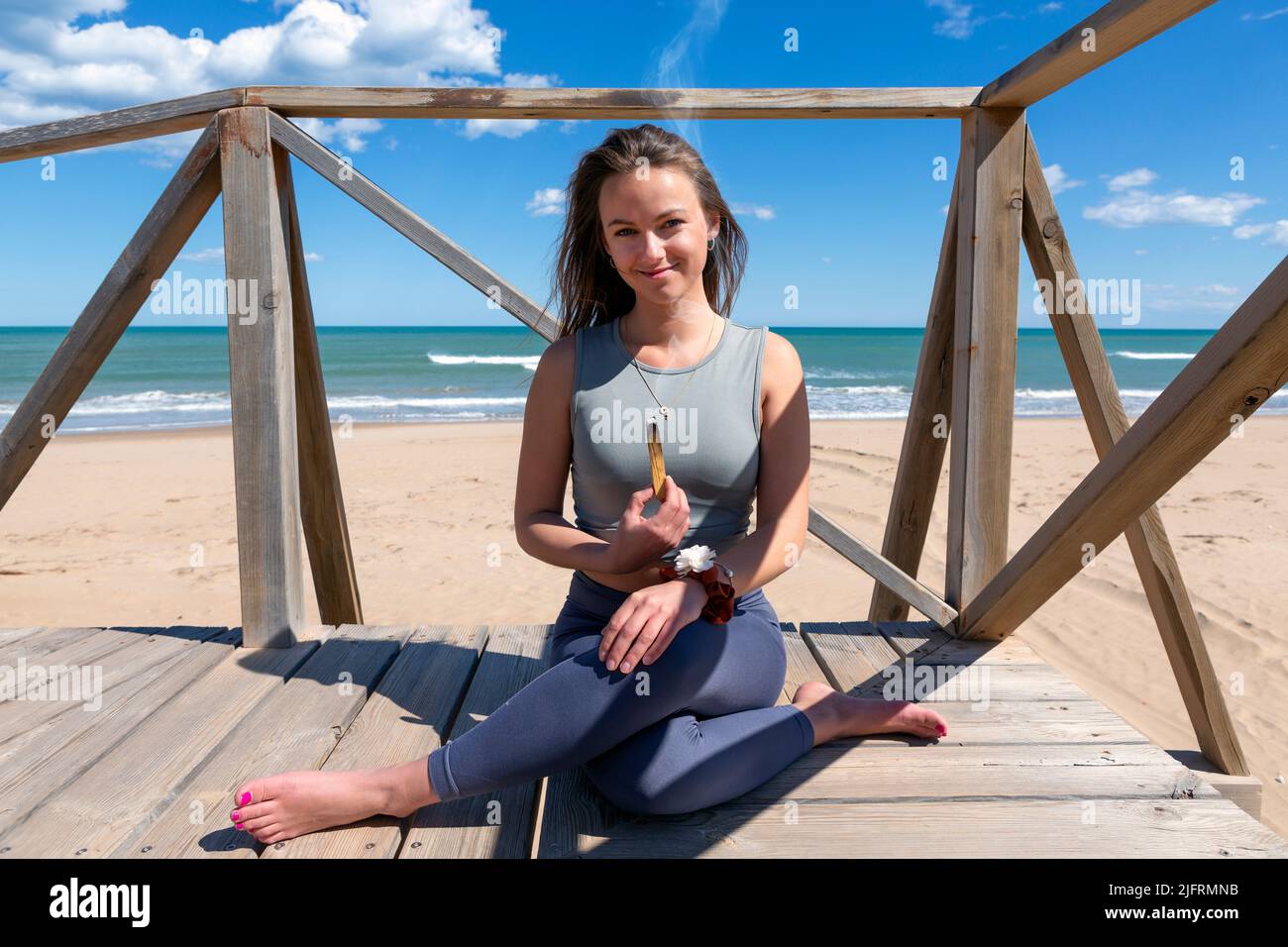 belle jeune femme méditant par la plage avec palo santo Banque D'Images