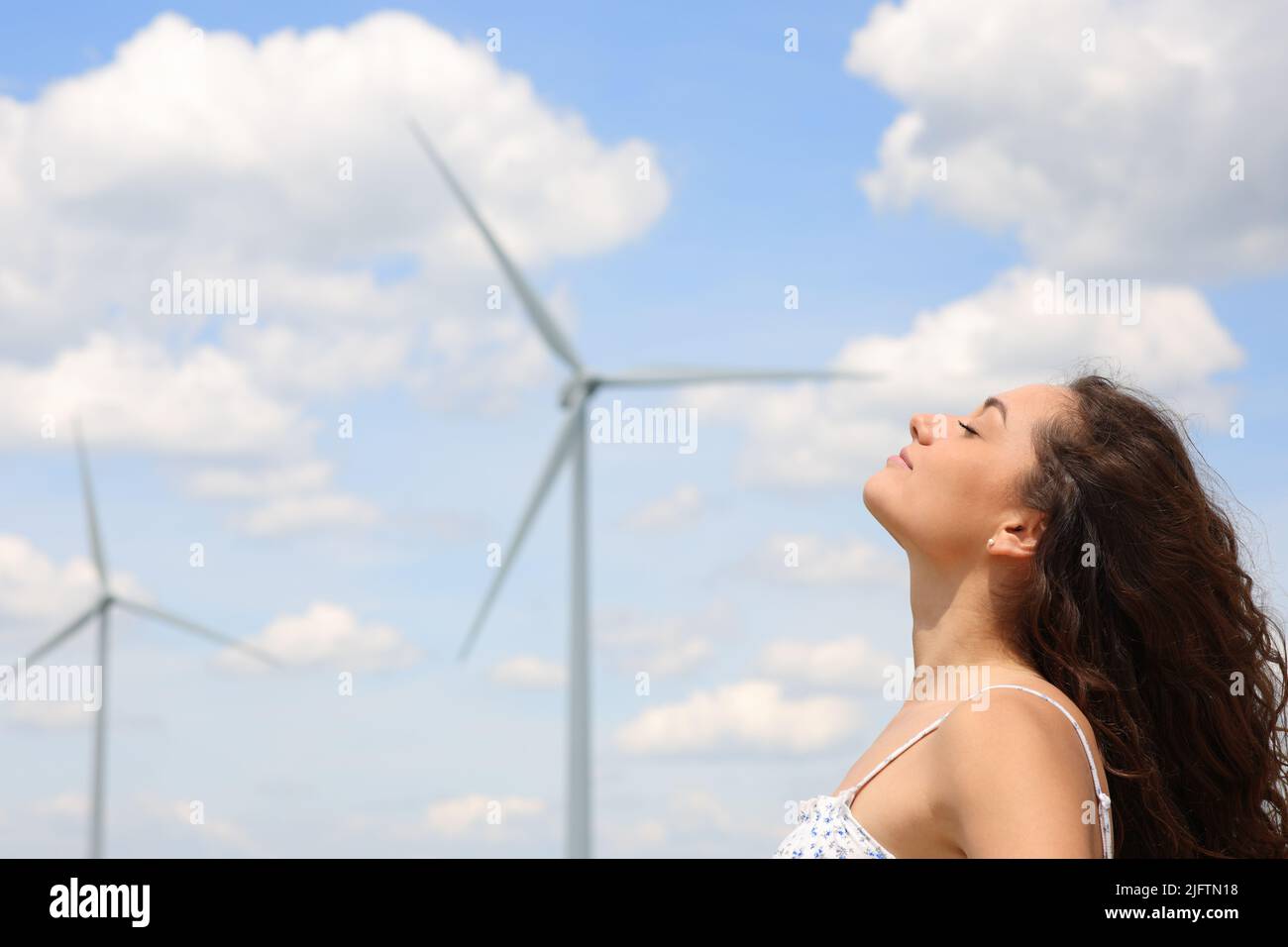 Profil d'une femme détendue respirant de l'air frais dans une ferme éolienne Banque D'Images