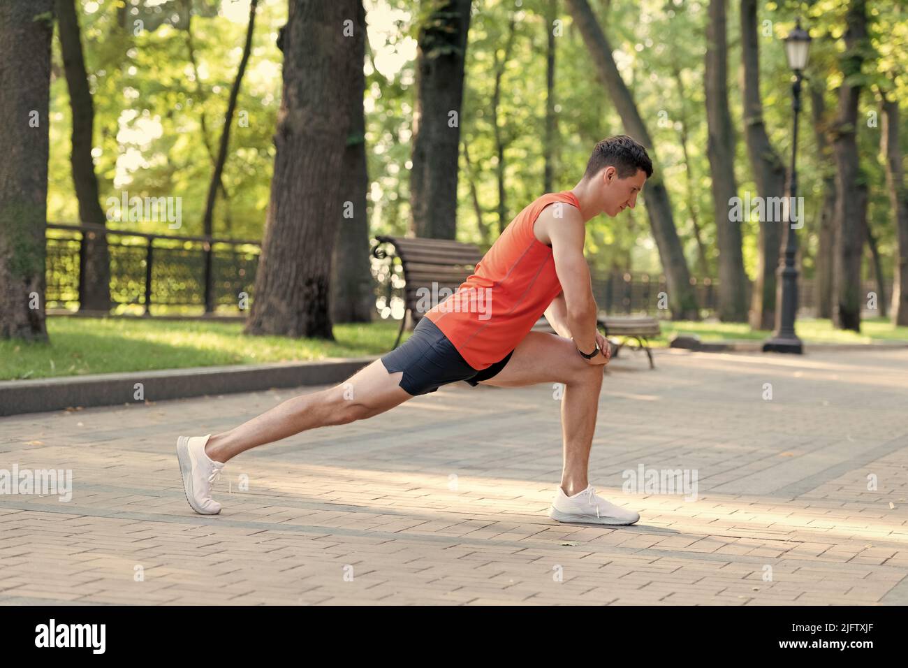 Sportsman tenir la position de fente faire une routine d'étirement pendant l'entraînement sportif en plein air dans le parc, l'échauffement Banque D'Images