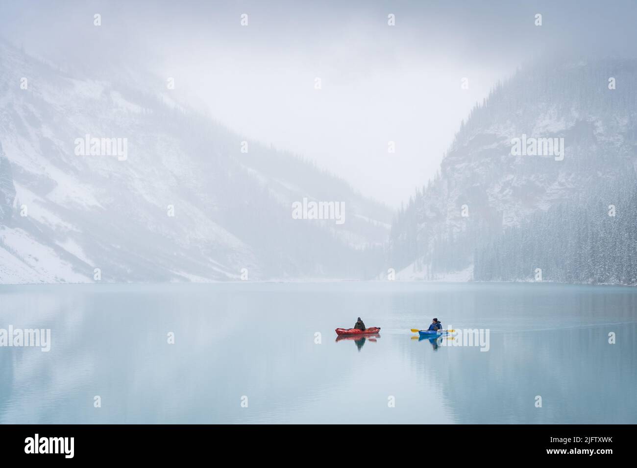 Deux kayakistes sur un lac alpin azur entouré de brume au début de l'hiver, parc Banff N., Canada Banque D'Images