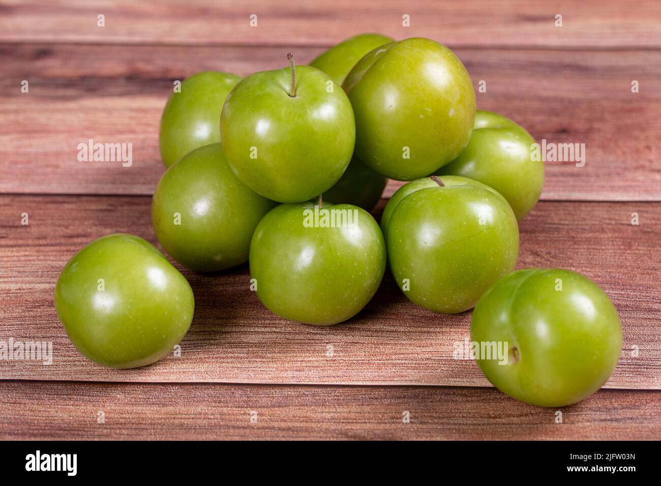 Prune verte sur fond de bois. Tas de prunes vertes. Gros plan Banque D'Images