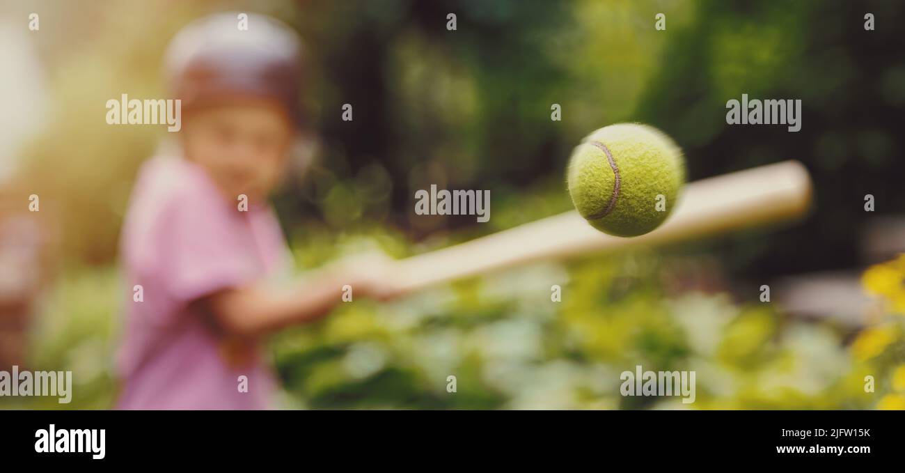 petite fille qui frappe une balle de tennis avec une batte de baseball au parc. entraînement de batte. espace de copie Banque D'Images