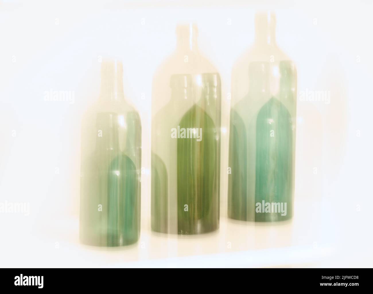 Design artistique de vieilles bouteilles en verre avec effet de mouvement de blury, isolé sur fond blanc. Lumière colorée floue abstraite sur trois verres verts Banque D'Images