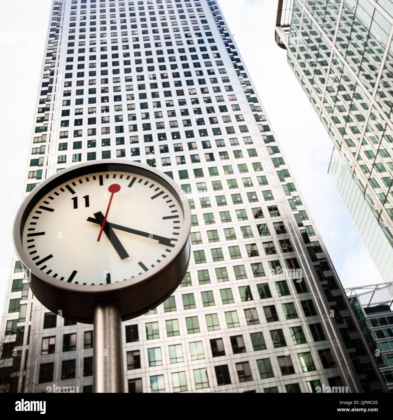 Horloges des Docklands, Londres, Royaume-Uni. Une vue basse et grand angle de la tour Canary Wharf en face de l'une des six horloges publiques de Konstantin Grcic. Banque D'Images