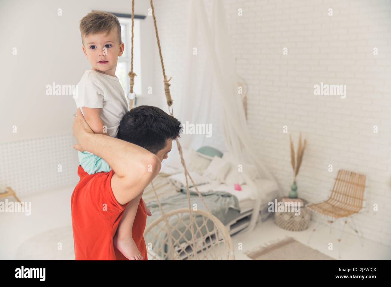 Petit garçon caucasien de circonscription le cou de son père dans la salle de séjour, concept de paternité. Photo de haute qualité Banque D'Images