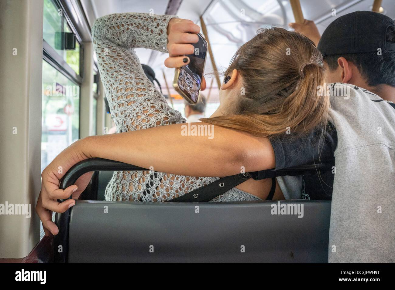 Vus de l'arrière derrière eux, deux jeunes passagers de bus, une femme dont la tête repose sur l'épaule d'un jeune homme pendant leur voyage dans le sud de Londres, le 5th juillet 2022, à Londres, Angleterre. Banque D'Images
