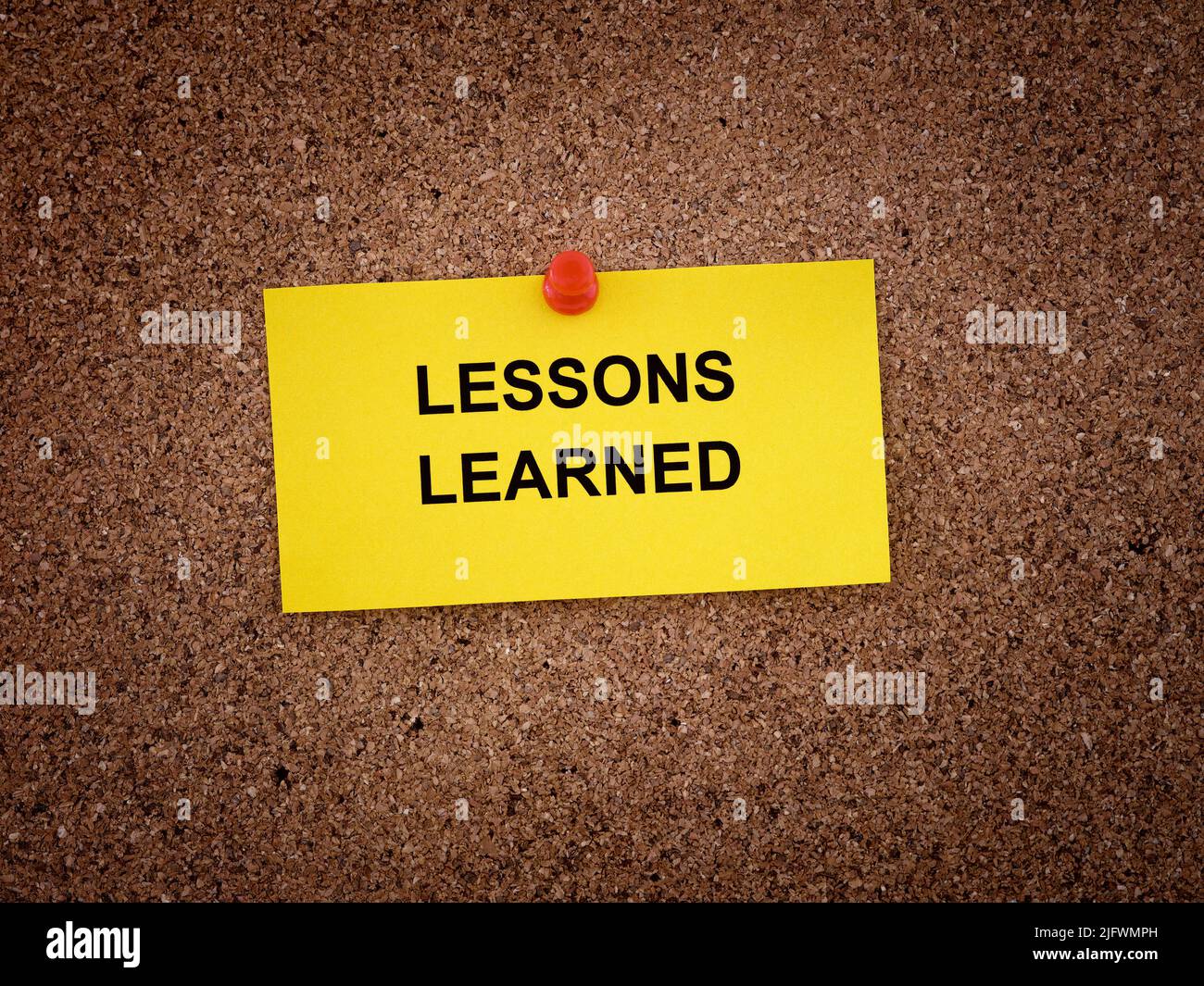Une note papier avec les mots leçons apprises écrit sur elle épinglée à un panneau de liège. Gros plan. Banque D'Images