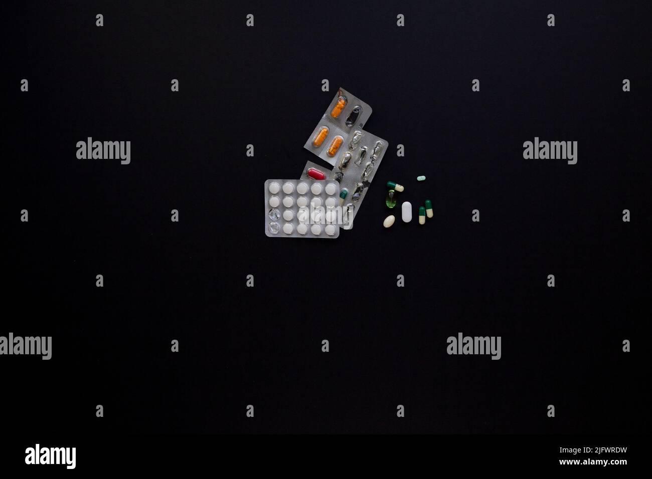 plaquettes thermoformées et pilules médicales dispersées sur une table noire Banque D'Images
