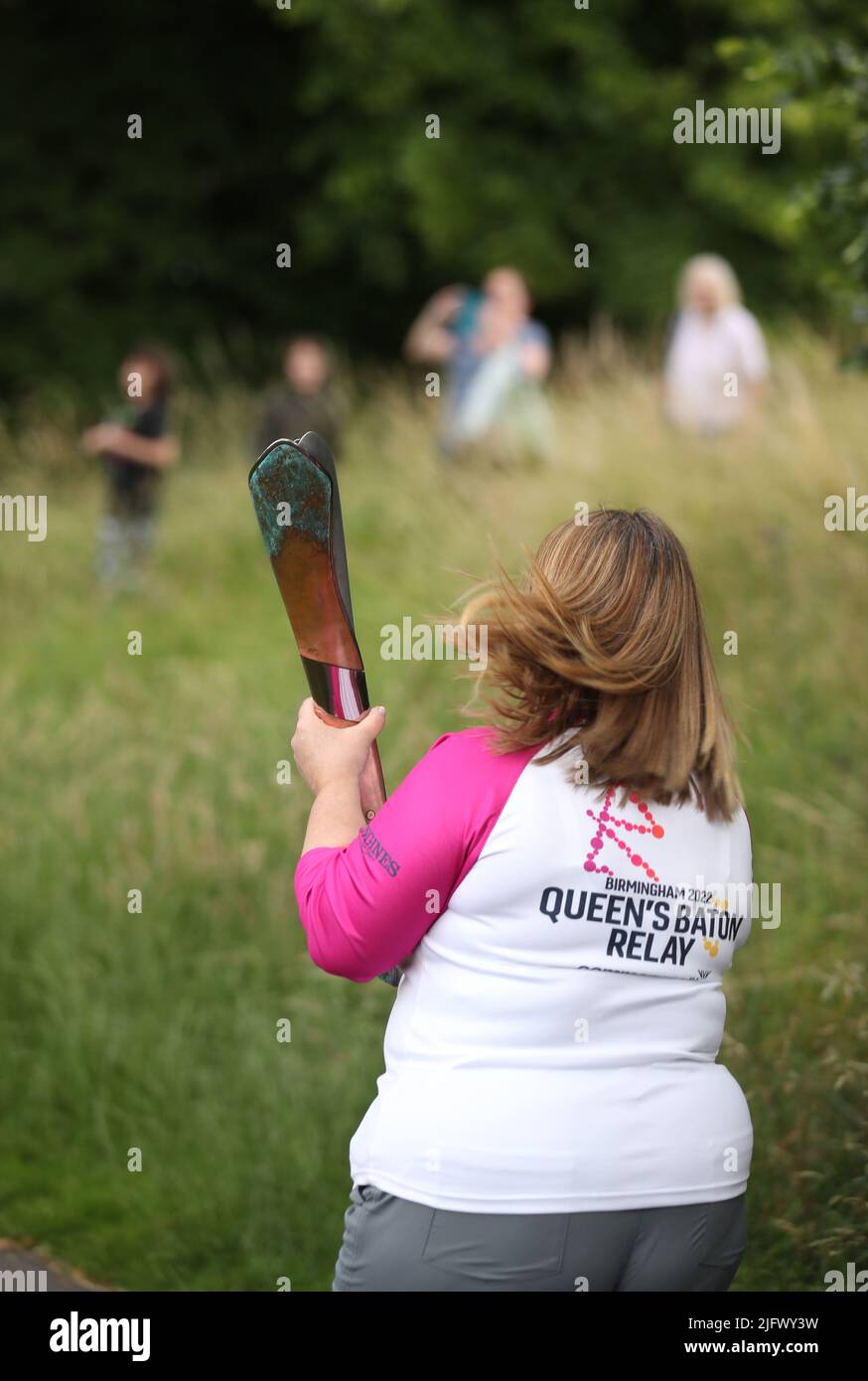 Un Beaton Bearer tient le Queen’s Baton lors d’une visite de l’équipe Queen’s Baton Relay des Jeux du Commonwealth au parc Pittville à Cheltenham, Gloucestershire. Banque D'Images