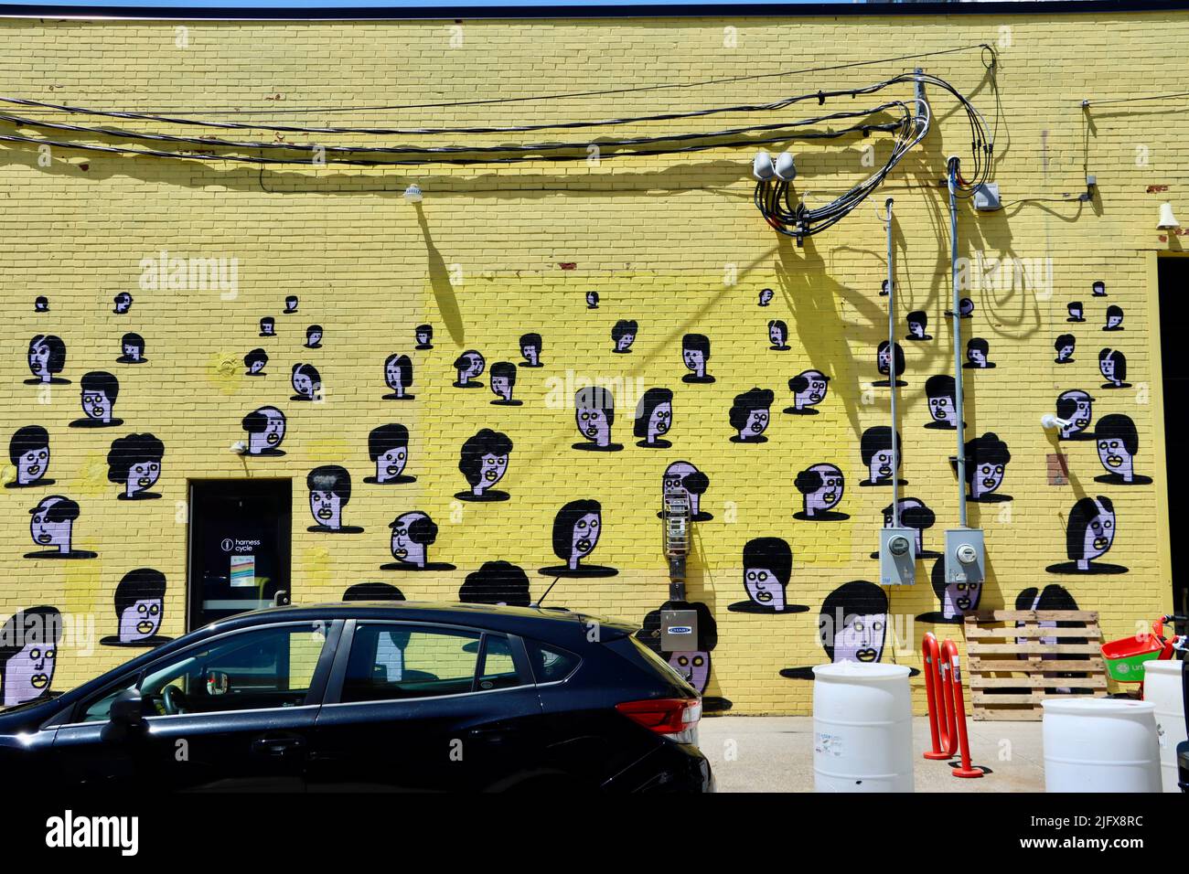 Têtes noires et blanches peintes sur fond jaune. Street art à Cleveland, Ohio, en mai 2022 Banque D'Images