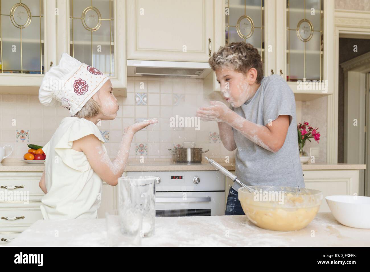 Frère et soeur ont du plaisir à jouer avec la farine dans la cuisine. Banque D'Images