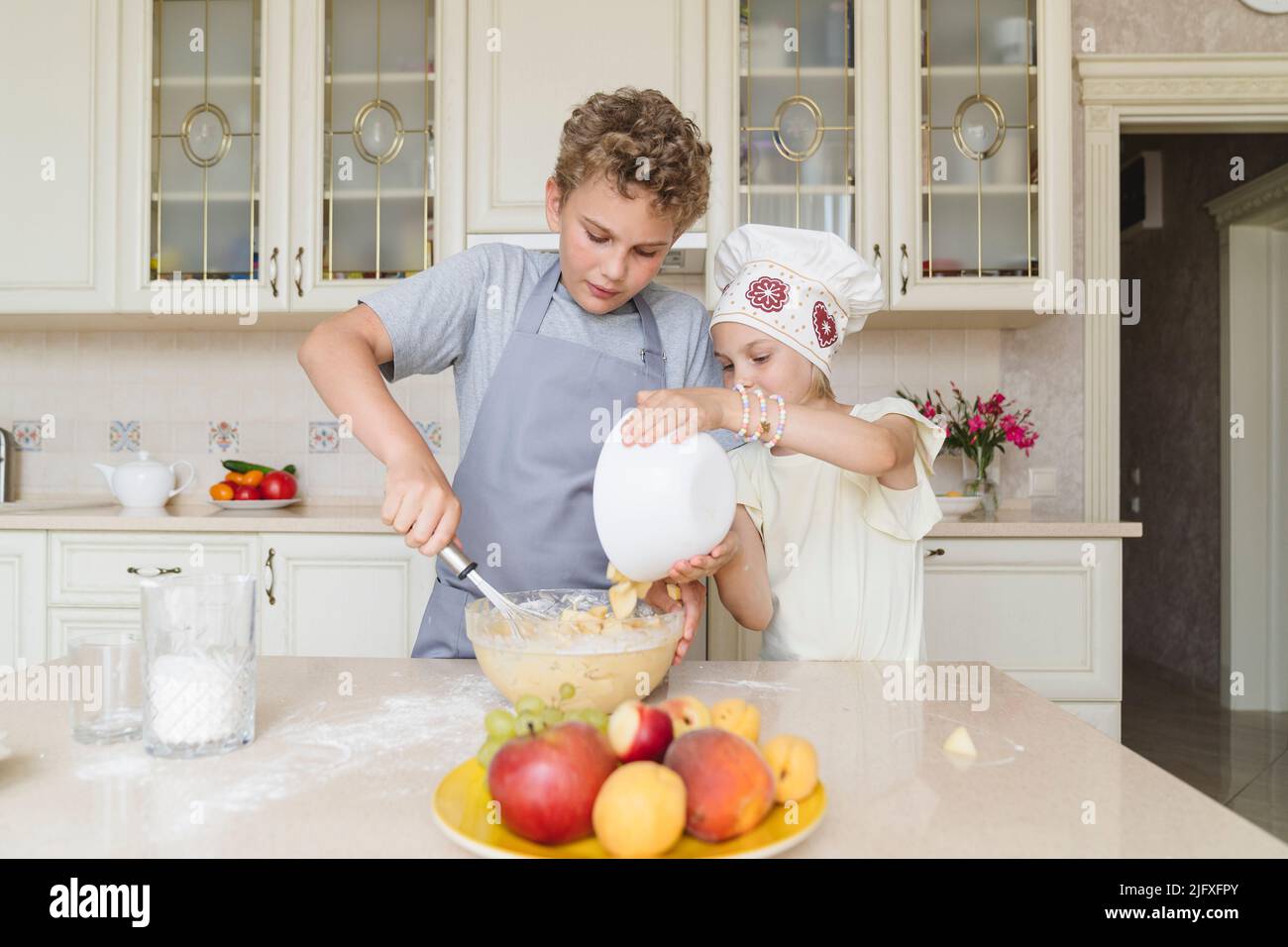 Les enfants préparent une tarte aux pommes dans la cuisine. Banque D'Images