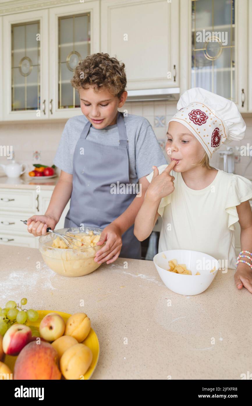 Les enfants ont plaisir à cuisiner de la tarte aux pommes dans la cuisine. Banque D'Images