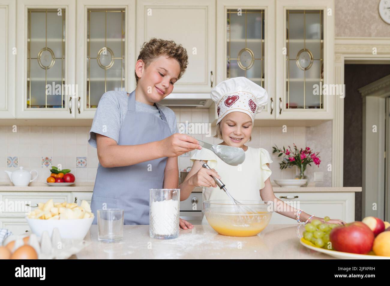 Frère et sœur cuisinent ensemble la pâte pour la tarte aux pommes. Banque D'Images