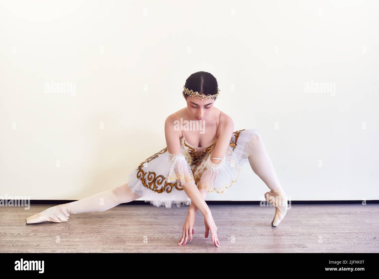 Ballerina jeune élégant en tutu blanc pratiquant des positions de ballet dans le studio Banque D'Images