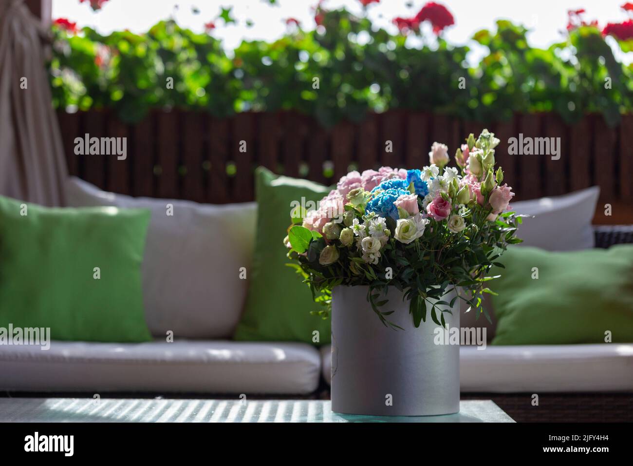 Un bouquet de roses dans une boîte sur une terrasse d'été. Un bouquet de roses roses roses et blanches décoré dans une boîte à chapeau créée par un fleuriste. Banque D'Images