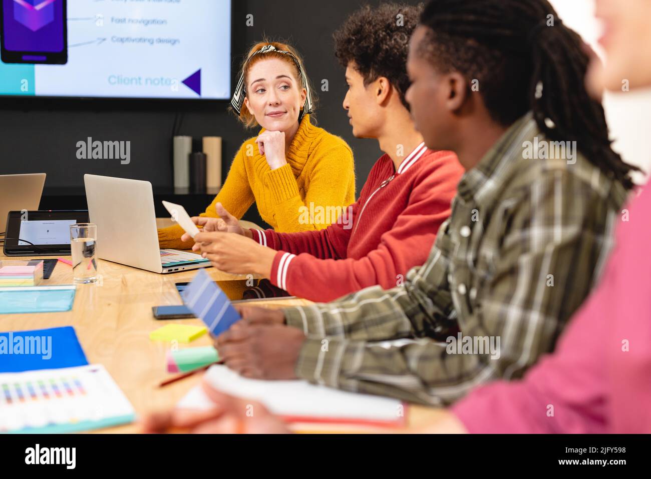 Une femme développeur d'applications caucasiennes discute avec un collègue biracial dans la salle du conseil d'administration au bureau Banque D'Images