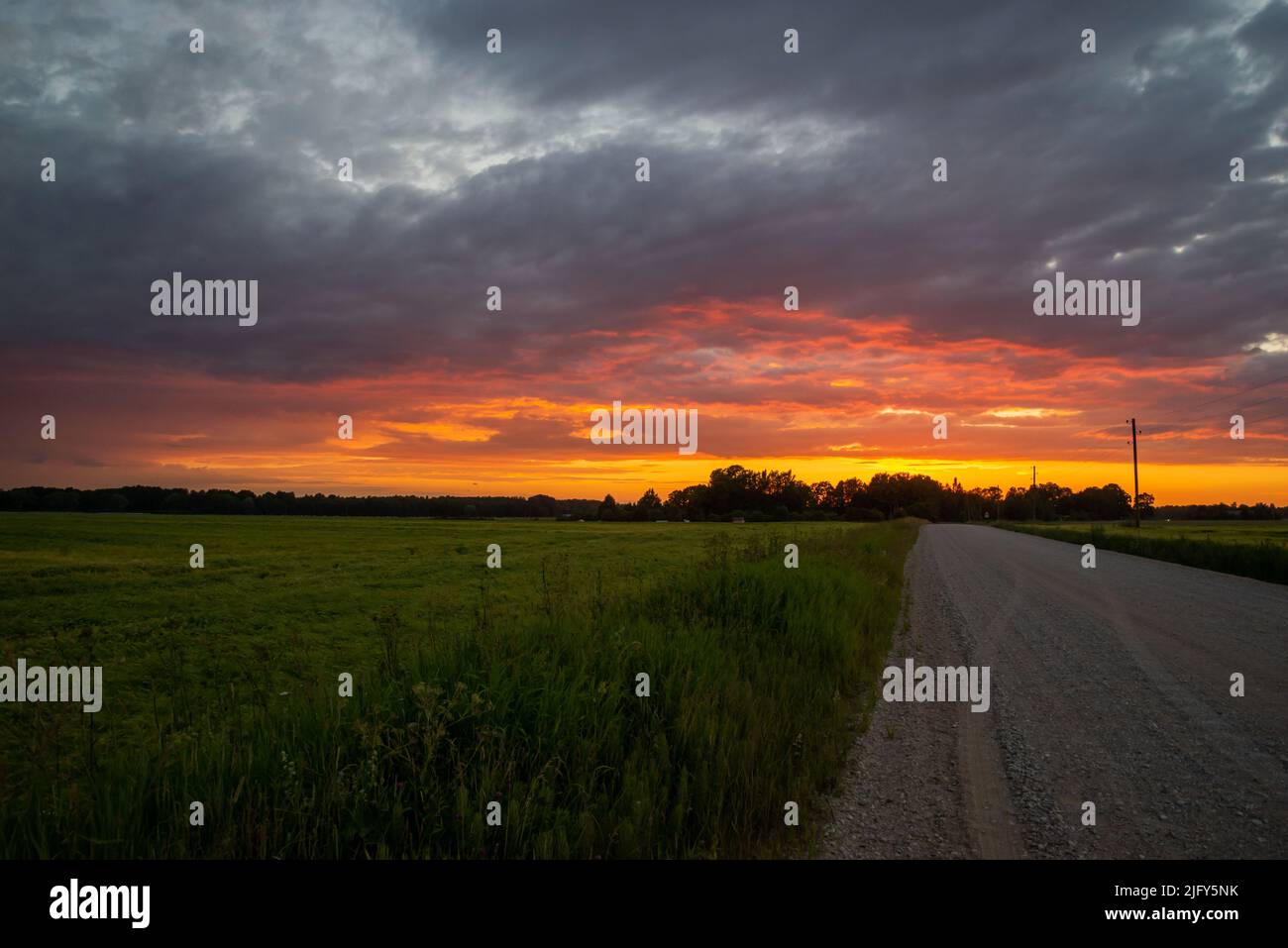 Paysage rural pittoresque avec une route de terre rompue au coucher du soleil. Banque D'Images
