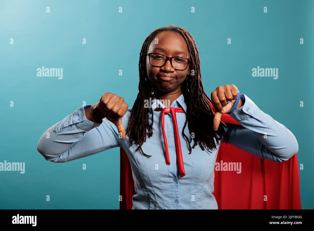 Dissipoted jeune adulte super-héros femme donnant des pouces vers le bas dissaproval doigts geste tout en regardant l'appareil photo. Un défenseur de la justice afro-américain puissant montrant le symbole de la main en désaccord. Banque D'Images