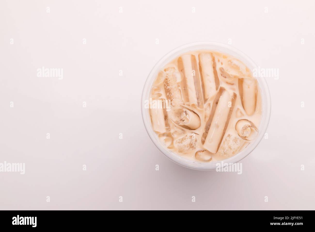 Vue de dessus du thé au lait avec de la glace dans du verre en plastique sur fond blanc Banque D'Images